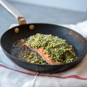 a salmon fillet in a pan with a cashew coating