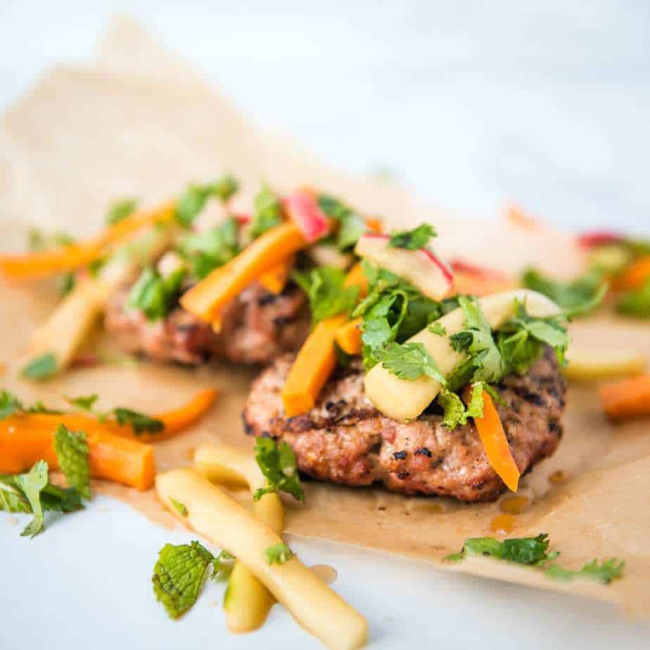Paleo AIP Banh Mi Burger on parchment paper with the pickled toppings, side view