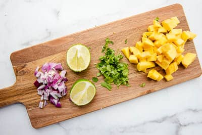 Mango salsa ingredients of red onion, lime, cilantro, and mango
