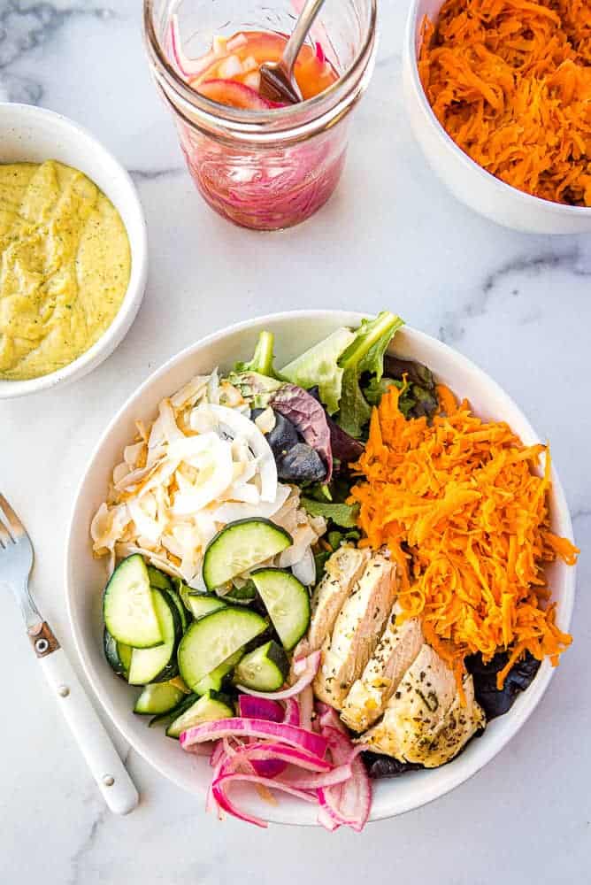 the finished Thai Chicken salad from above with a bowl of mango dressing, the pickled onions, and a bowl of the grated sweet potatoes