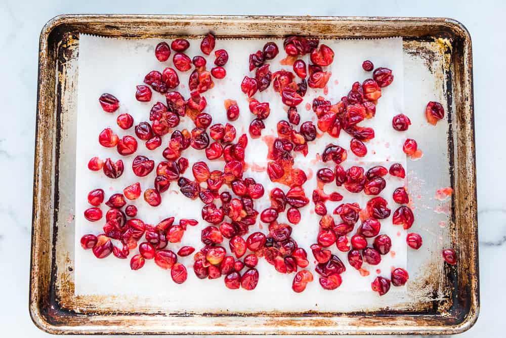popped fresh cranberries spread out on a baking sheet