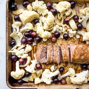 the fennel pork tenderloin laid out on a sheet pan with the cauliflower, grapes, and fennel surrounding it