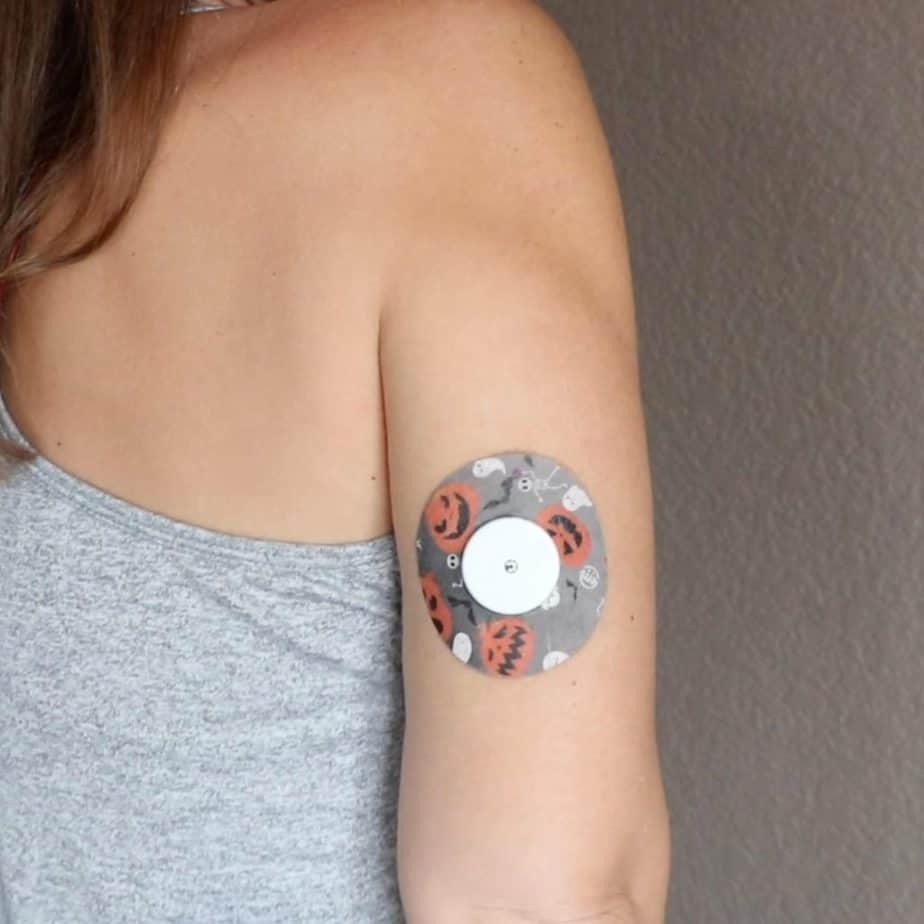 a woman's arm with a continuous glucose on the back, surrounded by a halloween sticker