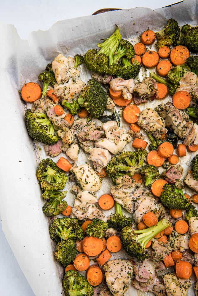 Vertical cose-up high angle view of sheet pan corner with roasted chicken, broccoli and carrots.